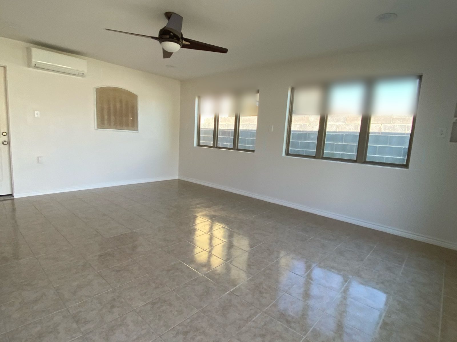 Inside the finished game room: big windows, a ceiling fan, a mini-split A/C and tile floors